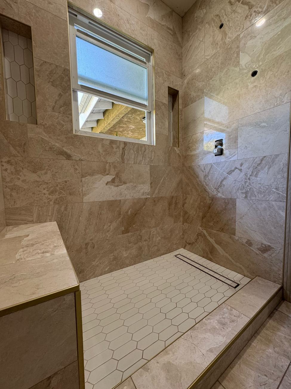 Shower renovation mid-construction: tile and built-in bench installed, glass and fixtures not yet added